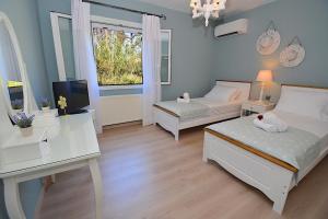 a bedroom with two beds and a desk and a television at Villa Jasmine Blossom in Gouvia