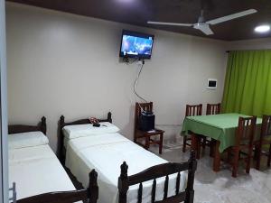 Habitación con 2 camas y TV en la pared. en Aparthostel Cataratas del Iguazu en Puerto Iguazú