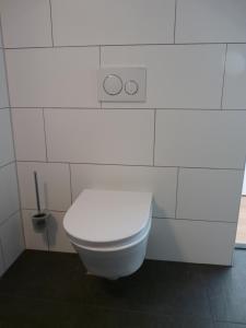 a white toilet in a white tiled bathroom at Bij Paul in Almere in Almere