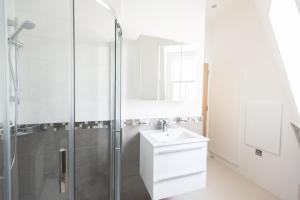 a white bathroom with a sink and a shower at The Soho Loft - Elegant & Modern 1BDR in London