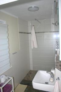 a white bathroom with a sink and a shower at Ferienwohnung Am See 55 in Bad Saarow
