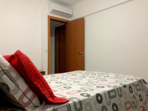 a bedroom with a bed with a red pillow on it at Lindo Village Imbassai in Mata de Sao Joao