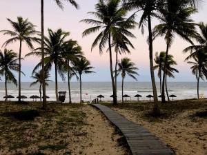 un chemin sur une plage avec des palmiers et l'océan dans l'établissement Lindo Village Imbassai, à Mata de São João