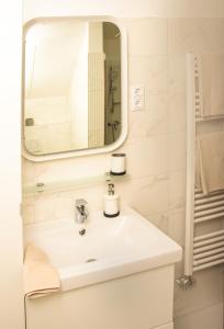 W łazience znajduje się biała umywalka i lustro. w obiekcie Centrum Apartman w mieście Cegléd