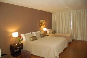 a hotel room with two beds and two lamps at Hotel de la Cité in Rosario +47 photos