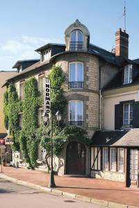 un grand bâtiment en briques avec un panneau devant lui dans l'établissement Hôtel Normandie Spa, à Bagnoles-de-l'Orne