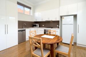 a kitchen with white cabinets and a wooden table and chairs at Waterstreet Apartment in Albury