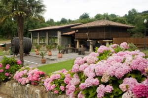 a garden with pink flowers in front of a building at El Foyu in Colunga
