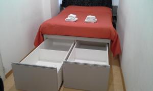 ein kleines Bett mit einer roten Decke und weißen Schubladen in der Unterkunft Departamento Estudio 1 in Neuquén