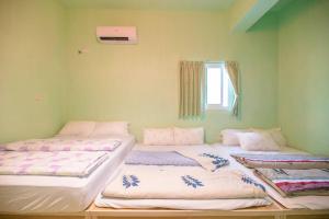 three beds in a room with a window at Penghu Color FIsh Homestay in Huxi