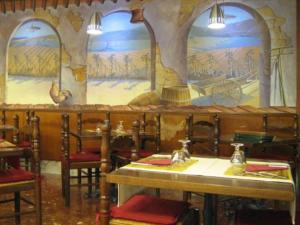 a dining room with tables and chairs and paintings on the wall at Hotel Da Cesare in Stresa