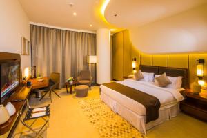 um quarto de hotel com uma cama grande e uma televisão em Arch Hotel em Manama