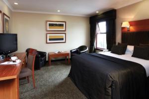 a hotel room with a bed and a desk and a television at Best Western Garfield House Hotel in Chryston