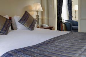 a bedroom with a bed with a phone and a chair at Old Hunstanton Le Strange Arms Hotel in Hunstanton