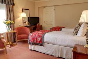 a hotel room with two beds and a desk at Old Hunstanton Le Strange Arms Hotel in Hunstanton