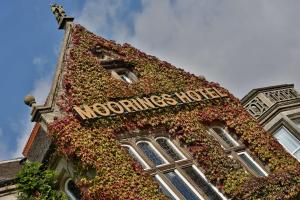 a building covered in ivy with a sign on it at Best Western Motherwell Centre Moorings Hotel in Motherwell