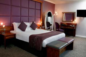 a hotel room with a large bed and a mirror at B/W Plus Lancashire Manor Hotel in Skelmersdale