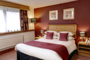 フロッドシャムにあるBest Western Frodsham Forest Hills Hotelの赤い壁のベッドルーム1室(大型ベッド1台付)