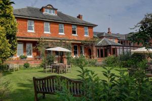 una gran casa de ladrillo con mesas y sillas en el patio en BEST WESTERN Sysonby Knoll en Melton Mowbray