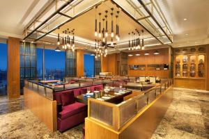 a restaurant with a bar with purple chairs and windows at Grand Hyatt Kochi Bolgatty in Cochin