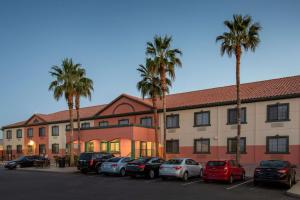 un edificio con auto parcheggiate in un parcheggio con palme di Baymont by Wyndham Phoenix I-10 near 51st Ave a Phoenix