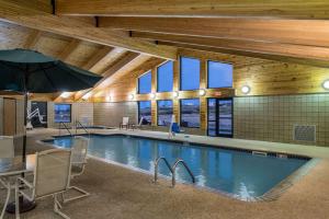 una piscina con sillas y una sombrilla en un edificio en AmericInn by Wyndham Belle Fourche en Belle Fourche