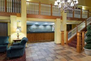 a lobby with a staircase and chairs and a chandelier at AmericInn by Wyndham Republic in Republic