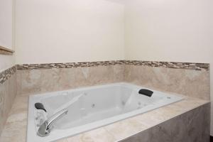 a bath tub sitting in a bathroom next to a sink at AmericInn by Wyndham Mount Pleasant in Mount Pleasant