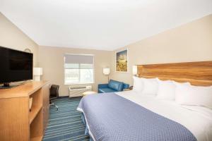 a hotel room with a bed and a flat screen tv at Days Inn & Suites by Wyndham Kearney NE in Kearney