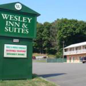 a green sign in front of a building at Wesley Inn & Suites in Middletown