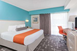 ein Hotelzimmer mit einem großen Bett und einem Schreibtisch in der Unterkunft Howard Johnson by Wyndham Mystic in Mystic
