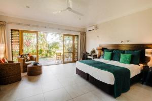 a bedroom with a large bed with green pillows at Sinalei Reef Resort & Spa in Maninoa