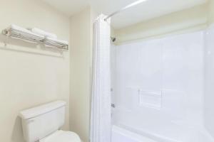 y baño blanco con aseo y ducha. en Super 8 by Wyndham Burleson Fort Worth Area, en Burleson