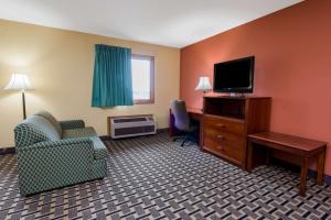 a hotel room with a tv and a couch and a chair at Super 8 by Wyndham Staunton in Staunton