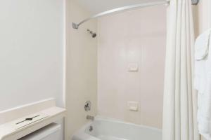a white bathroom with a shower and a white tub at Super 8 by Wyndham Old Saybrook in Old Saybrook