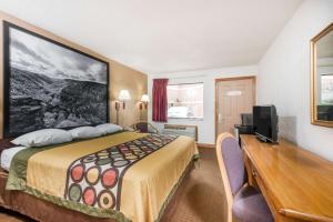 Habitación de hotel con cama, escritorio y TV. en Super 8 by Wyndham Bridgeport/Clarksburg Area en Bridgeport
