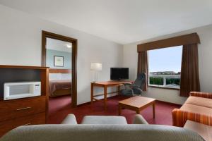a hotel room with a bed and a desk with a television at Super 8 by Wyndham Yellowknife in Yellowknife