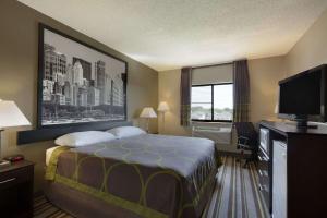 a hotel room with a bed and a flat screen tv at Super 8 by Wyndham Bridgeview/Chicago Area in Bridgeview