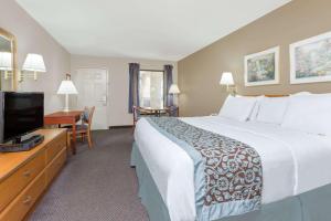 a hotel room with a large bed and a flat screen tv at Days Inn by Wyndham Elberton in Elberton