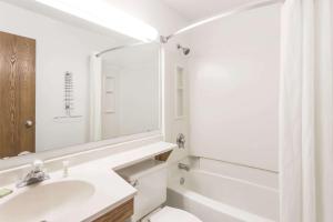y baño con lavabo, aseo y espejo. en Super 8 by Wyndham Pontiac, en Pontiac