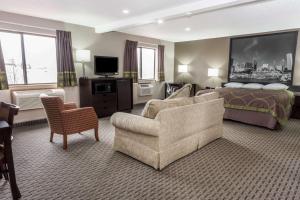 a hotel room with a bed and a couch and a chair at Super 8 by Wyndham Mundelein/Libertyville Area in Mundelein