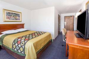 ein Hotelzimmer mit einem Bett und einem Schreibtisch mit einem TV in der Unterkunft Super 8 by Wyndham Pontiac in Pontiac