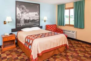 a hotel room with a bed and a chair at Super 8 by Wyndham Shipshewana in Shipshewana