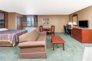 een hotelkamer met een bed, een bank en een tafel bij Super 8 by Wyndham Poplar Bluff Missouri in Poplar Bluff
