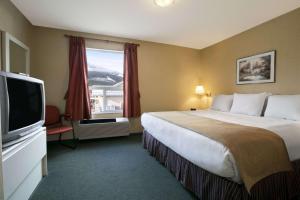 a hotel room with a large bed and a television at Super 8 by Wyndham Revelstoke BC in Revelstoke +35 photos