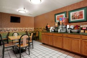 ein Restaurant mit einer Theke, einem Tisch und Stühlen in der Unterkunft Super 8 by Wyndham Peoria East in Peoria