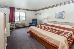 a hotel room with a bed and a chair at Super 8 by Wyndham Morris in Morris