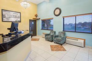 a waiting room with chairs and a clock on the wall at Super 8 by Wyndham Normal Bloomington in Bloomington