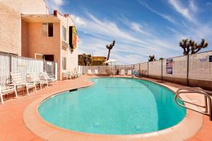 a large swimming pool with chairs and a building at Super 8 by Wyndham Yucca Val/Joshua Tree Nat Pk Area in Yucca Valley