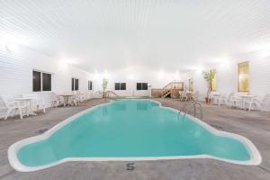 een groot zwembad in een witte kamer met tafels en stoelen bij Super 8 by Wyndham Driggs in Driggs